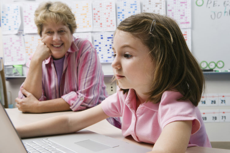 Girl and her teacher looking at a computer screen