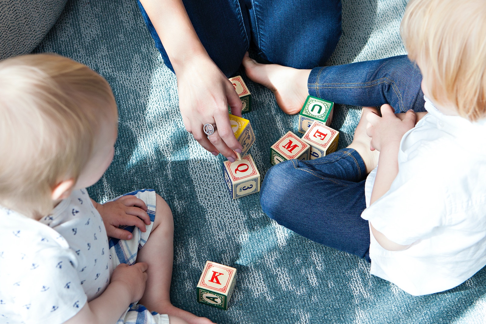 Two young children playing with letter blocks, developing their IQ from an early age