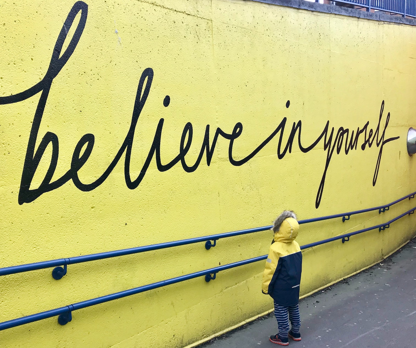 A young child reading "believe in yourself"