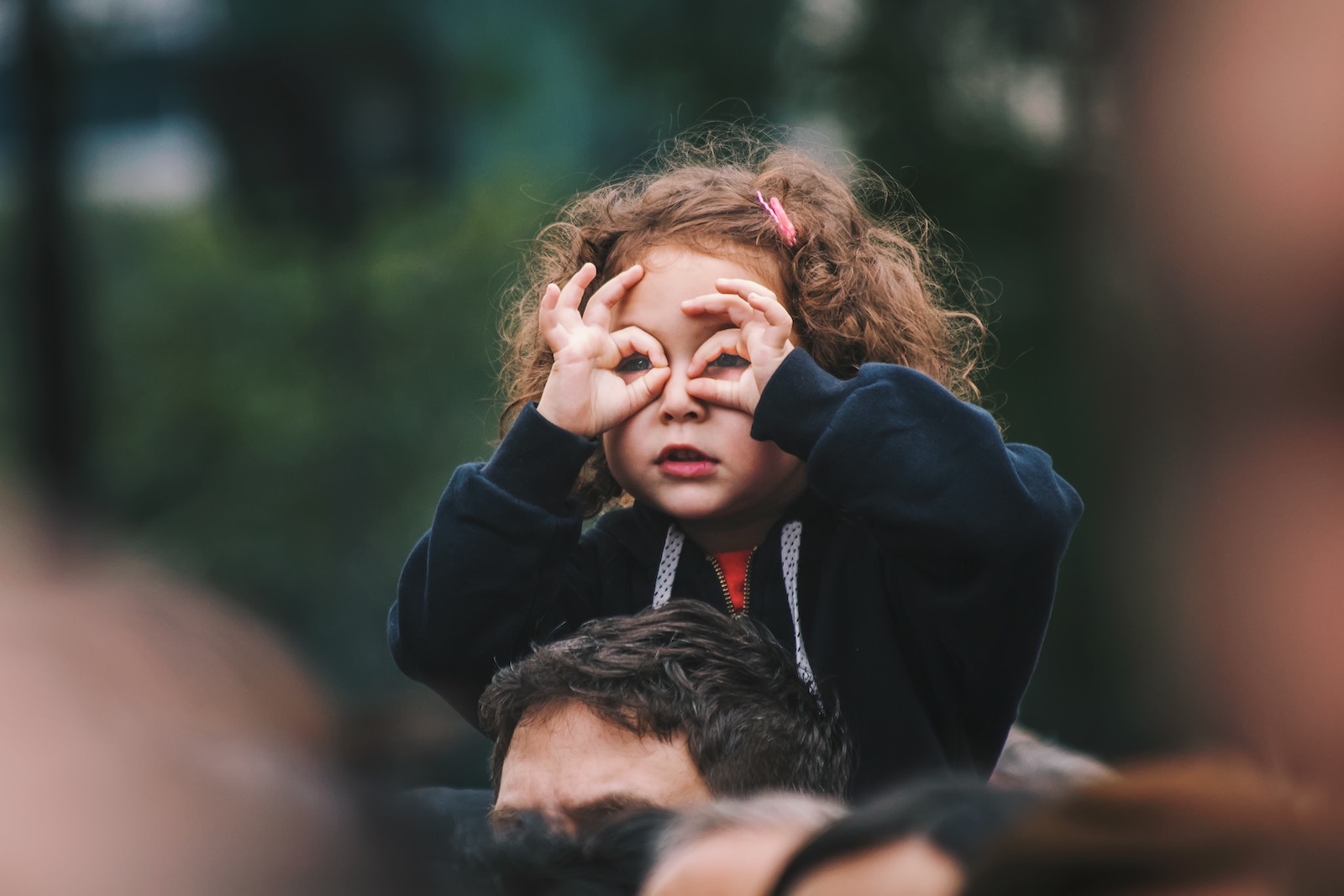 A young girl on her dad's shoulders. Developing her confidence.